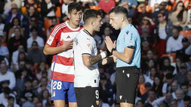 García Verdura, el árbitro del Valencia - Granada, recibe las quejas de los futbolistas.
