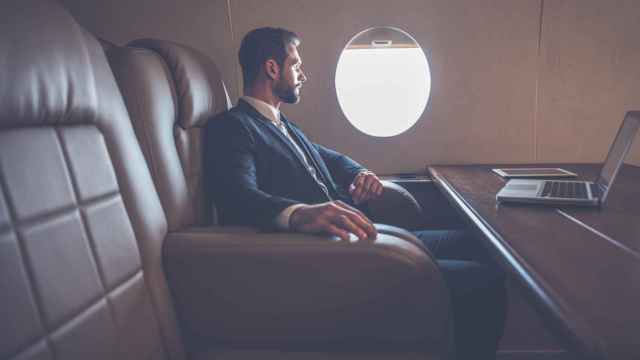 Un hombre con traje en un avión, en una imagen de archivo.