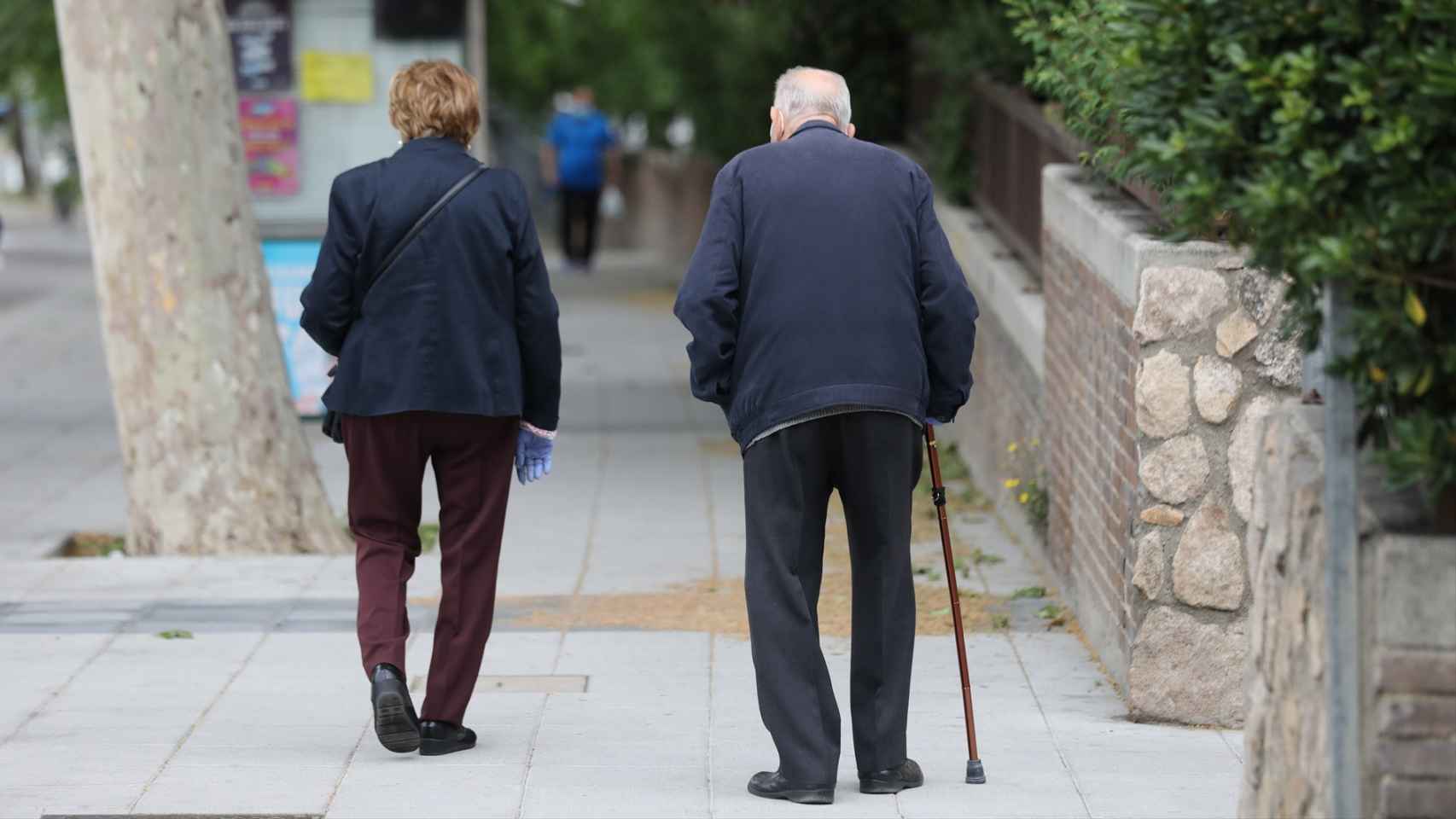 Una pareja de jubilados pasea por la calle.
