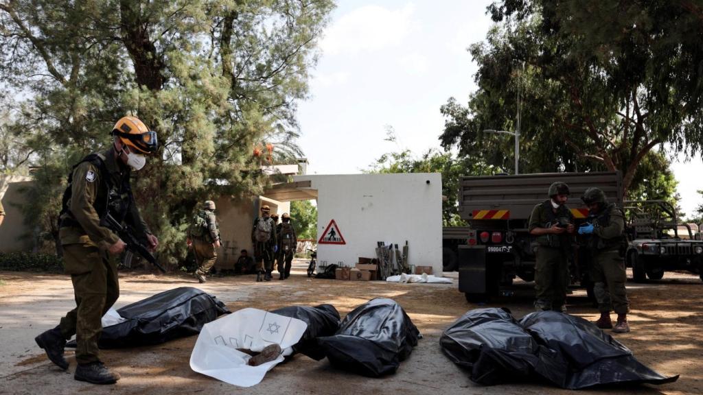 Miembros del Ejército de Israel, ante una fila de cadáveres embolsados en el kibutz de Kfar Aza, cerca de la frontera de Gaza.