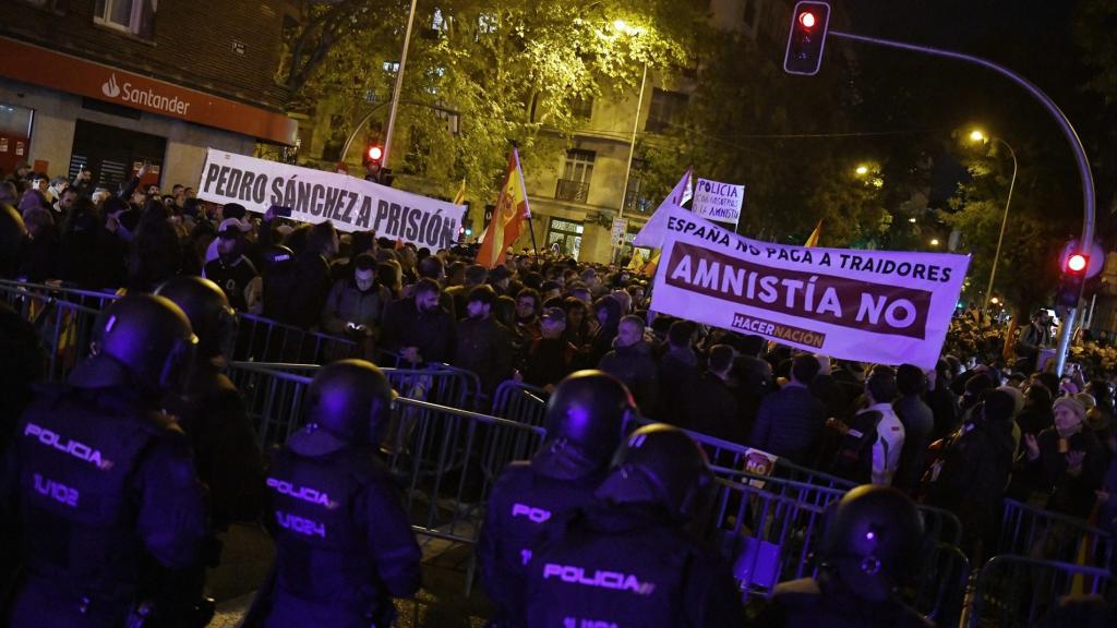 Decenas de personas con banderas y pancartas durante una concentración en contra de la amnistía, frente a la sede del PSOE en la calle Ferraz.