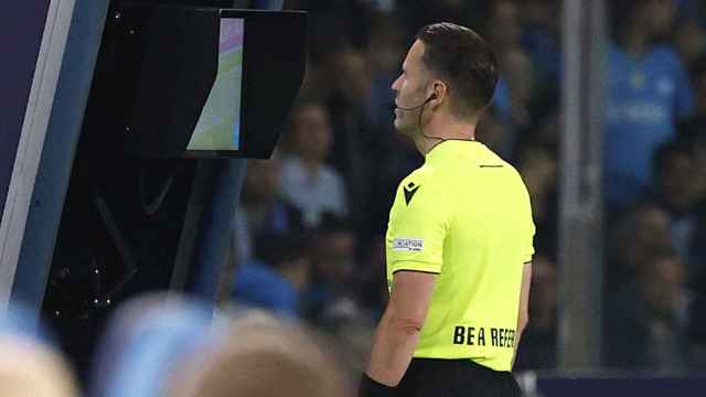 Danny Makkelie mira la pantalla del VAR revisando una jugada con el lema 'Be a referee' en su camiseta.
