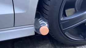 Botella de plástico entre el neumático y la carrocería.