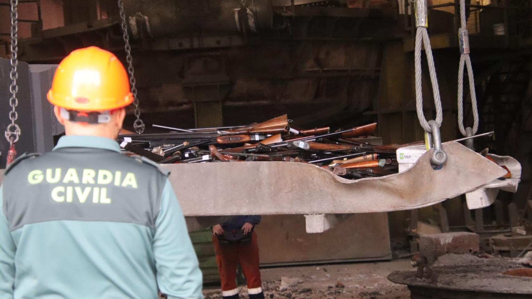 Un agente de la Guardia Civil frente a las armas que han sido destruidas