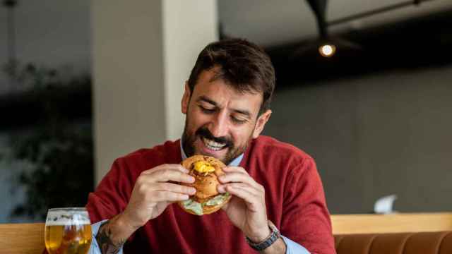 Imagen de archivo de un hombre a punto de comerse una deliciosa hamburguesa.