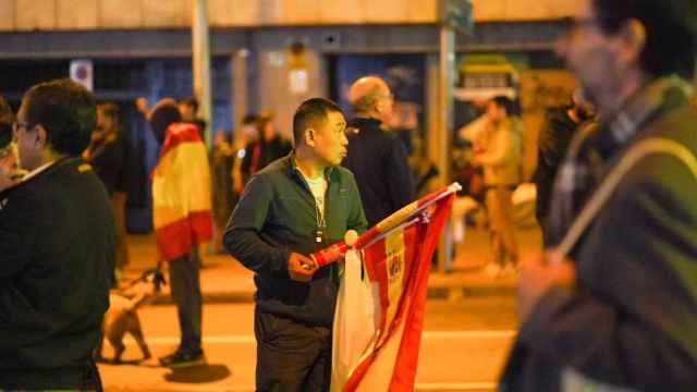 Un ciudadano chino trata de vender banderas de España en los aledaños de la calle Ferraz de Madrid, este martes.