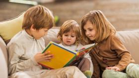 Niños leyendo juntos en un sofá.