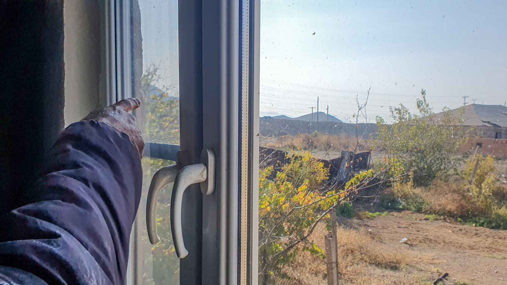 Un constructor armenio de Yerasj señala desde su ventana la posición militar desde los azeríes abren fuego con frecuencia..