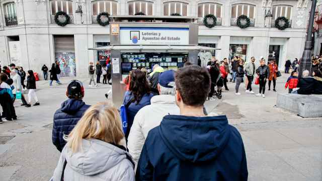 Varias personas hacen cola para comprar lotería en Madrid.