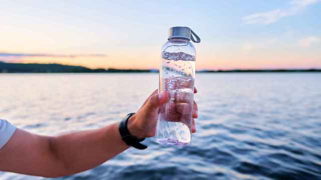 Una botella de agua con el mar de fondo.
