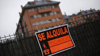 Un cartel de 'se alquila' frente a un bloque de pisos