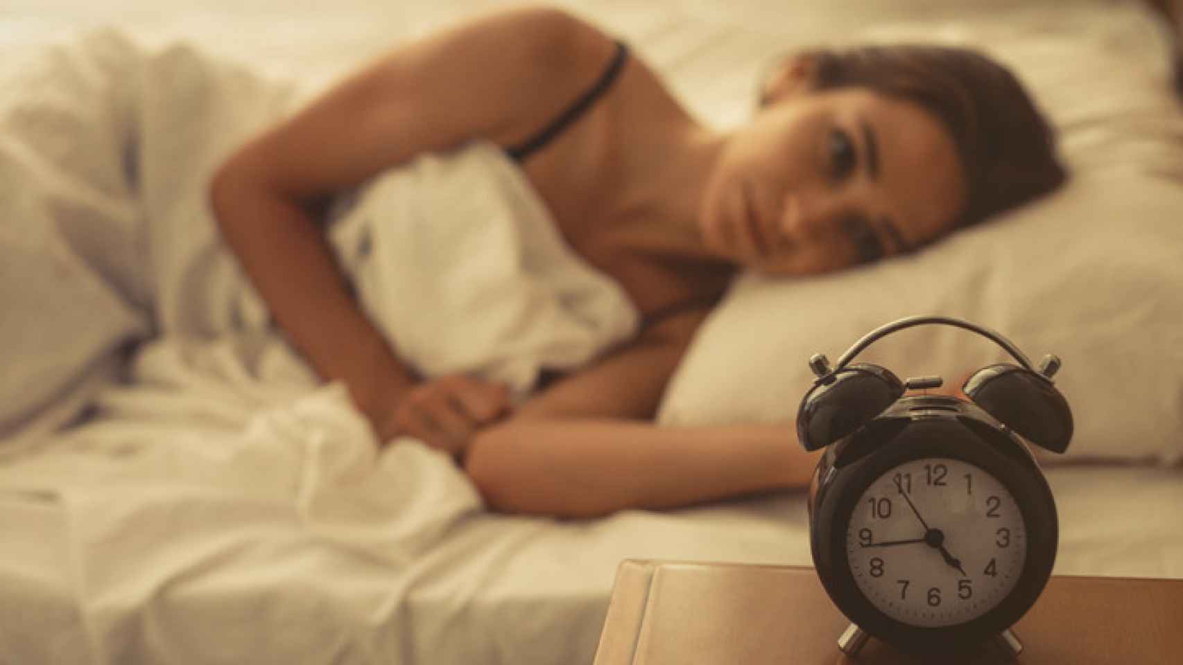 Imagen de archivo de una mujer mirando el despertador.