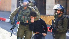 Dos soldados israelíes detienen a un niño palestino en Hebrón, en septiembre de 2021.