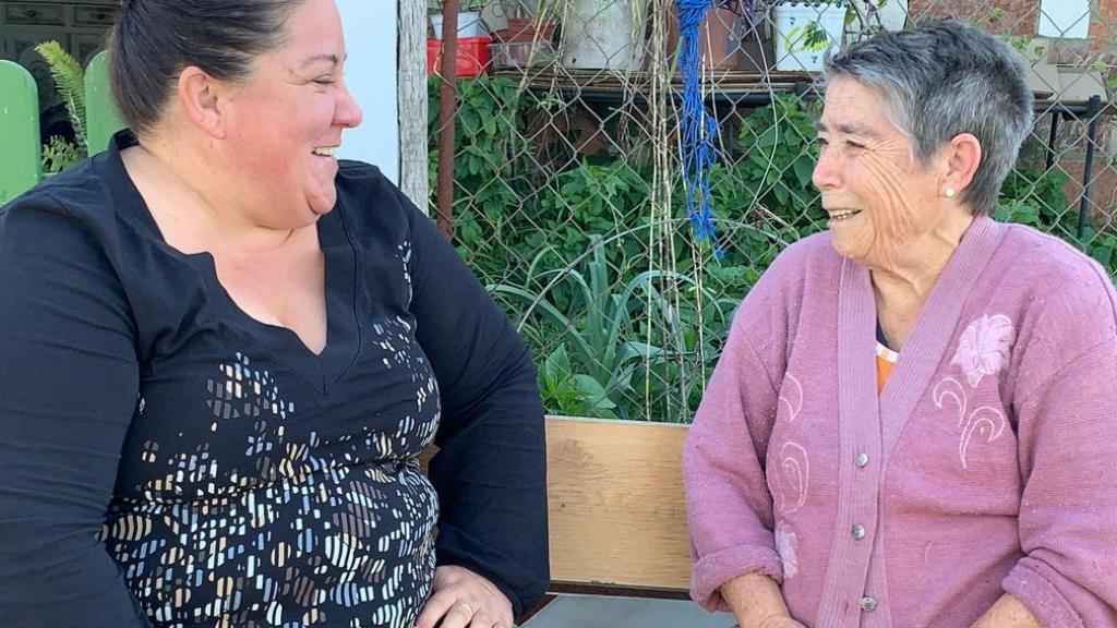 Madre e hija sonríen en la puerta de la vivienda, tras conocer que la finca ya es suya.