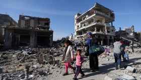 Una familia desplazada regresa a su hogar atravesando edificios destruidos, este viernes en Jan Yunis.