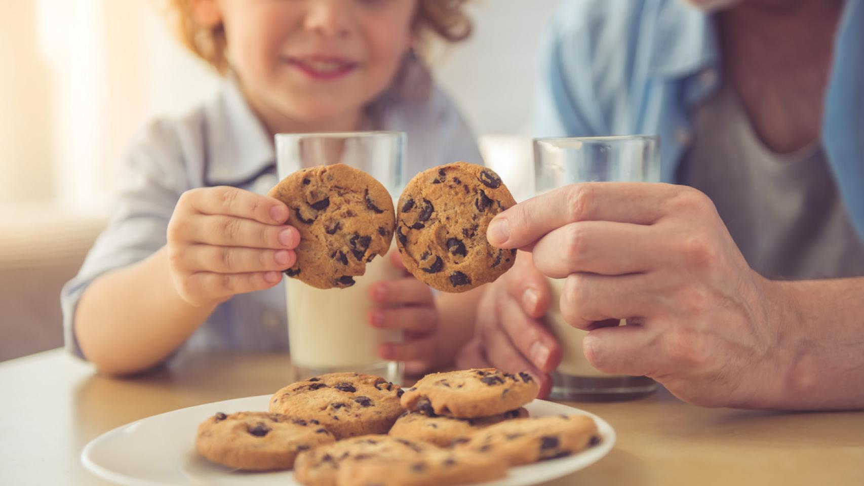 Un niño y un adulto comen galletas.