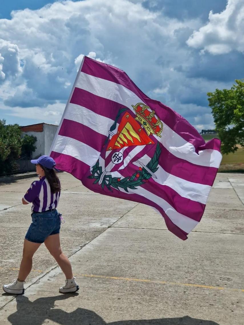 Una de las integrantes de la peña Dando Guerra con una bandera y el escudo antiguo del Real Valladolid