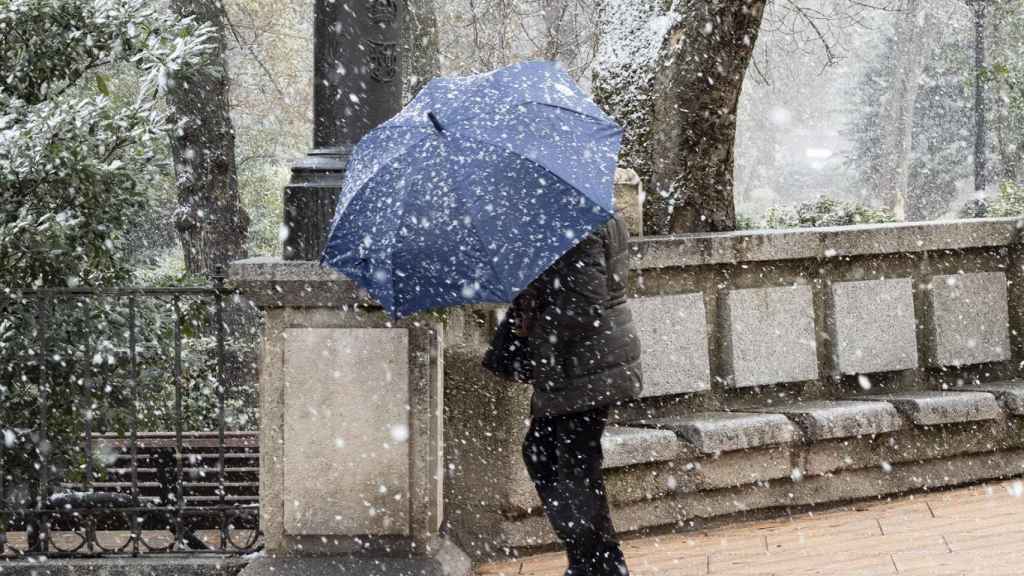 Una mujer se cubre con su paraguas bajo una intensa nevada en Cuenca