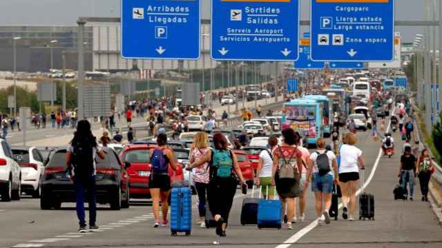 Numerosos viajeros tuvieron que caminar por la carretera para llegar al aeropuerto de El Prat por las protestas tras la sentencia del procés en 2019.