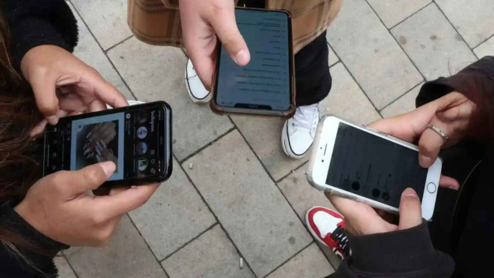 Un grupo de adolescentes mirando las redes sociales en sus teléfonos móviles.