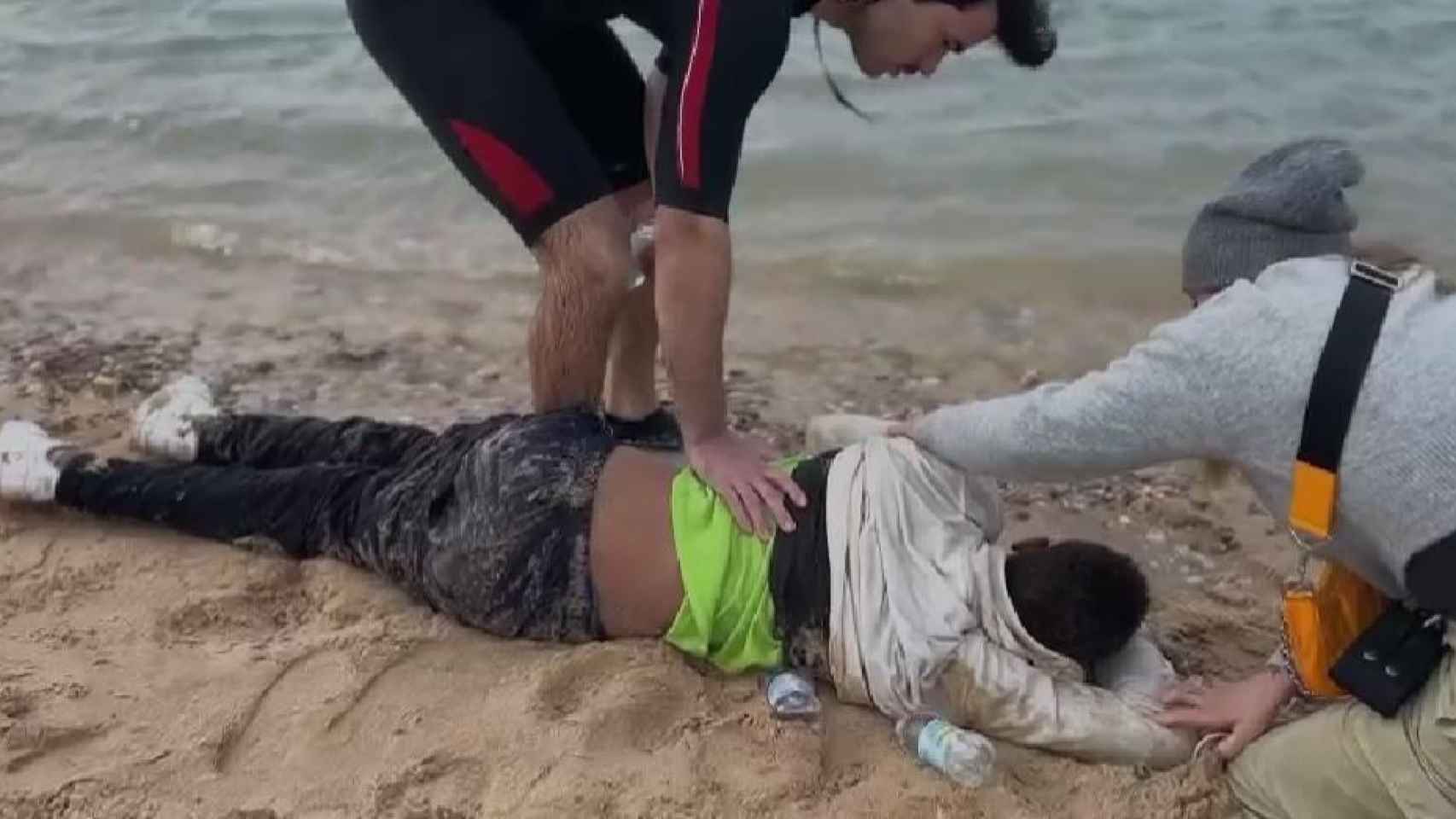 Uno de los jóvenes, en la orilla de la playa, tras ser reanimado.