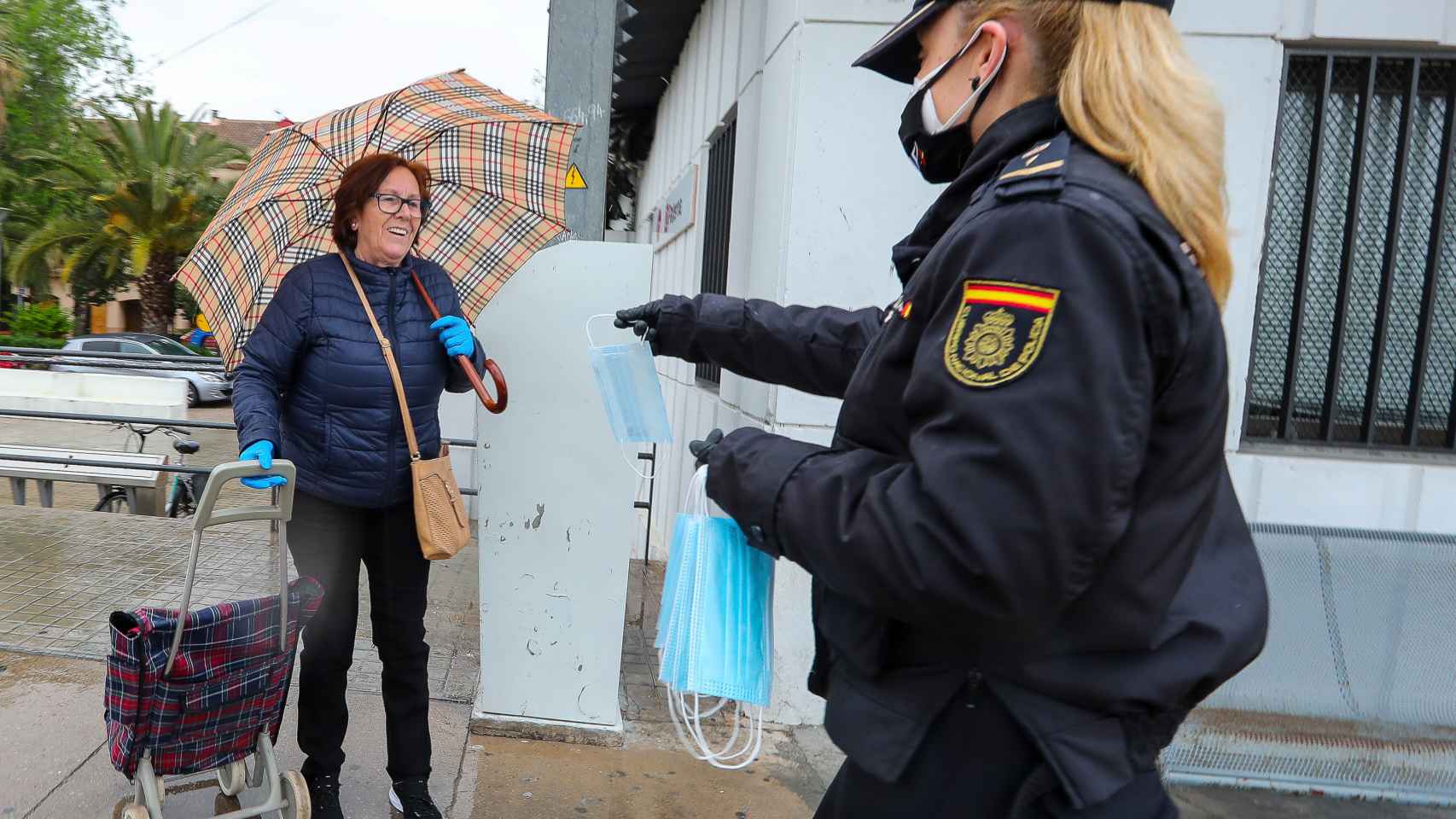 Una policía nacional entrega a una mujer una mascarilla en la calle, en una imagen de archivo.