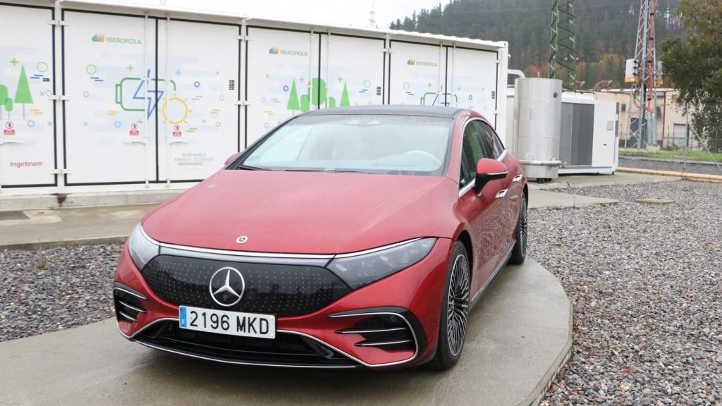 Un coche eléctrico frente a la batería que apoya al sistema eléctrico.