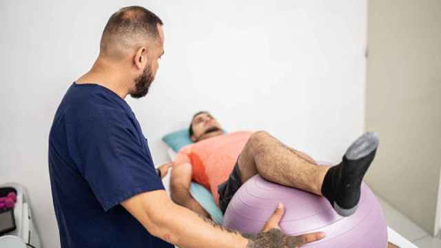 Fisioterapeuta dando terapia a un hombre.