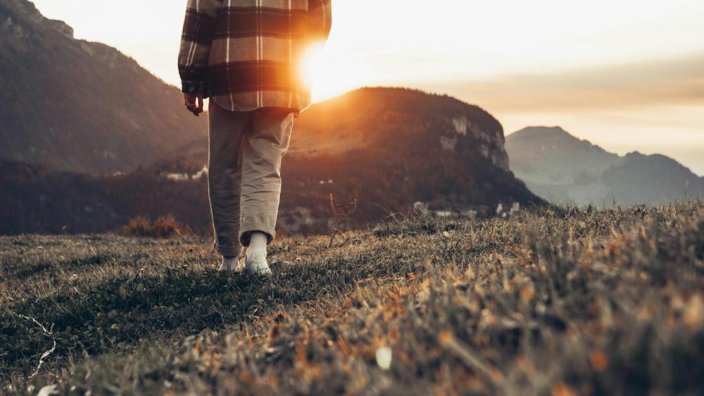 Imagen de una persona caminando en la montaña al atardecer.