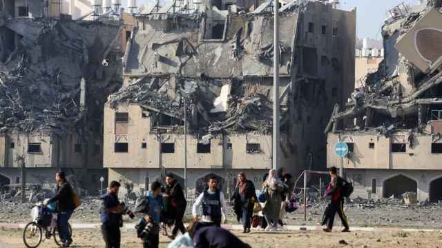 Los edificios yacen en ruinas mientras los palestinos cargan sus pertenencias tras los ataques israelíes contra edificios residenciales en Jan Yunis.
