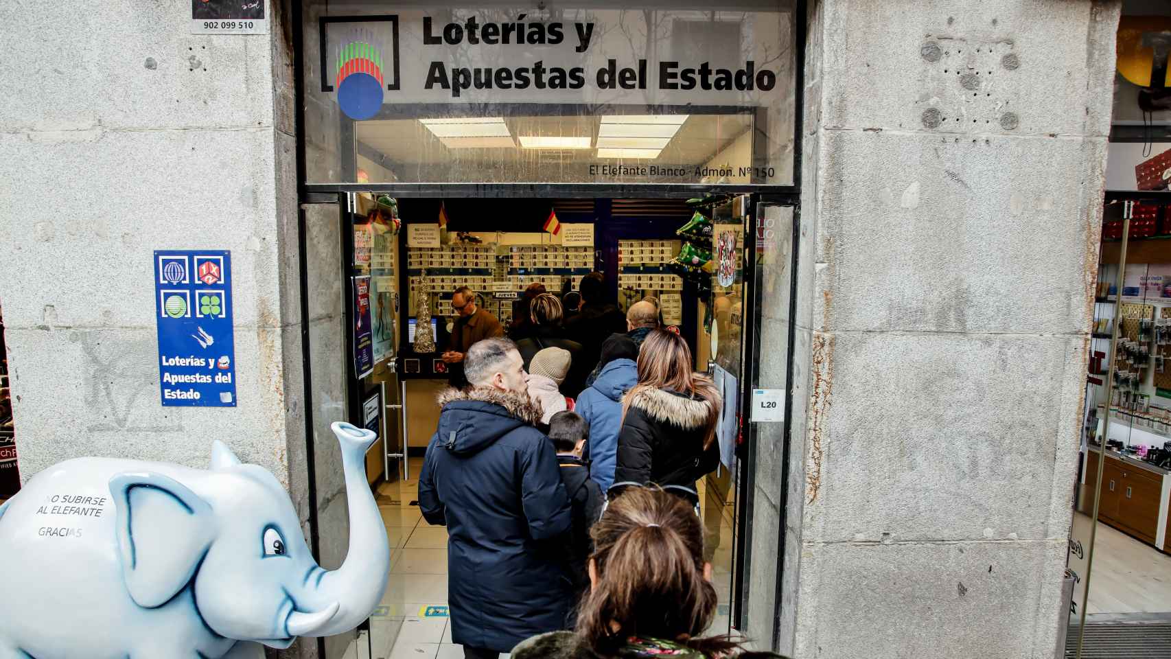 Varias personas hacen cola en una administración de Lotería de Madrid.