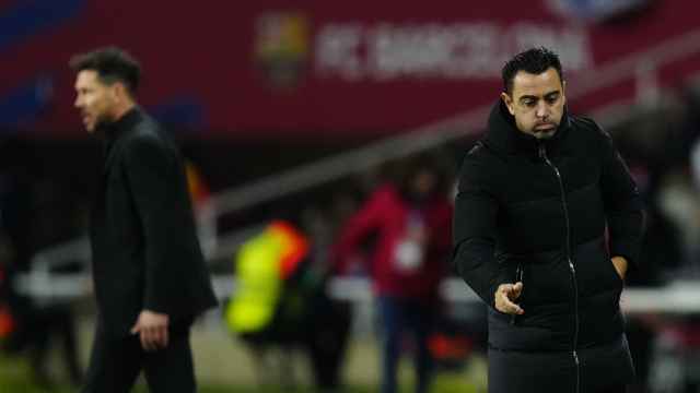 Simeone, de fondo, y Xavi, durante el Barcelona - Atlético de Madrid
