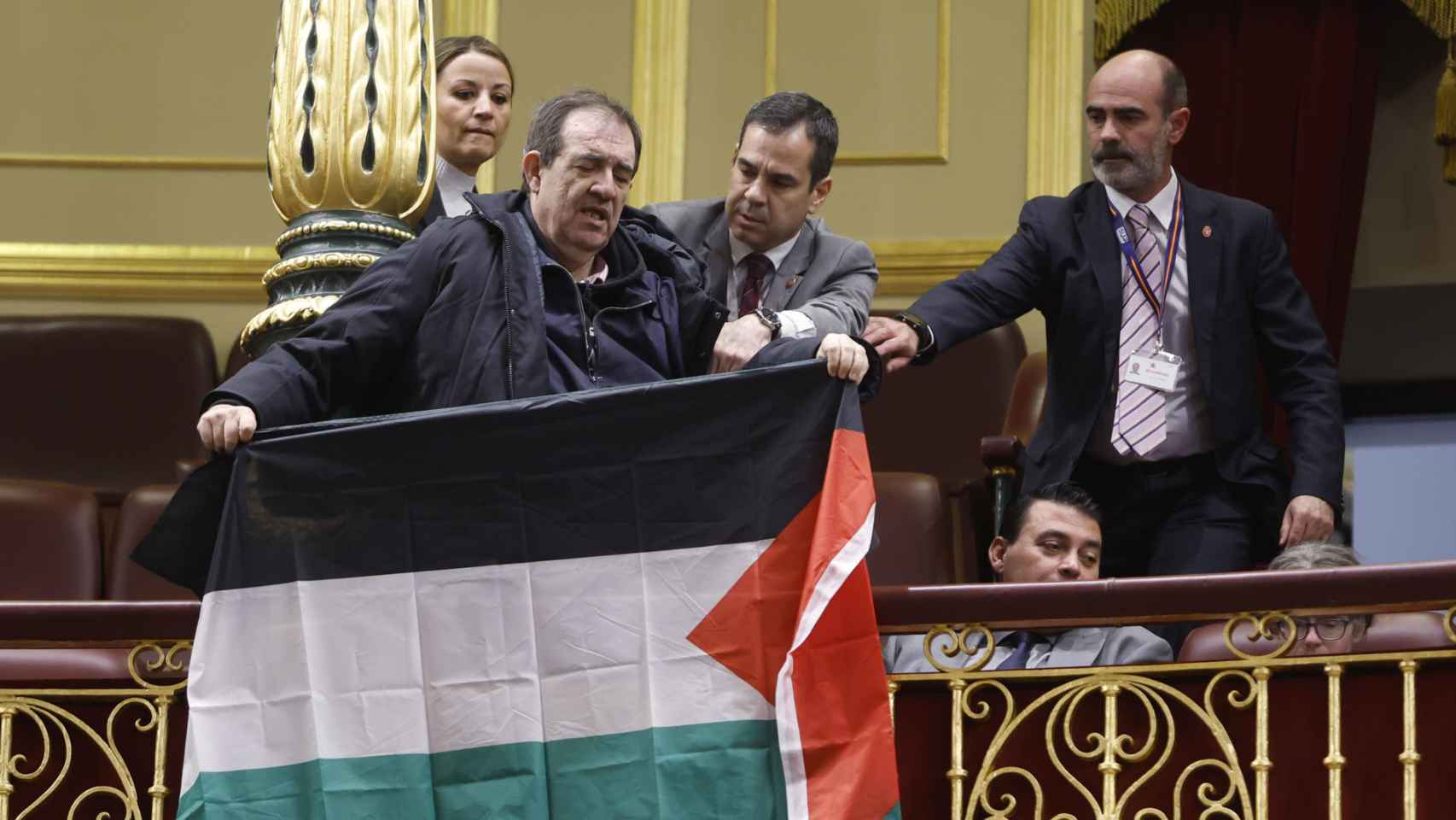 Un asistente despliega una bandera palestina durante el pleno del Congreso en el que comparece el ministro de Asuntos Exteriores, Unión Europea y Cooperación, José Manuel Albares.