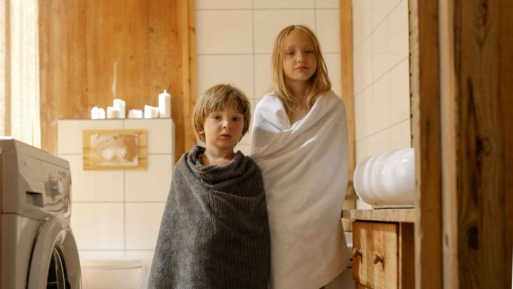 Imagen de dos niños enrollados con toallas en el baño
