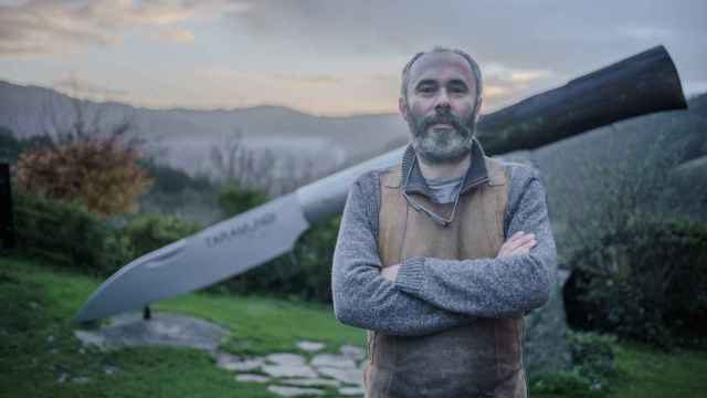 Juan Carlos Quintana es uno de los 35 artesanos de Taramundi que aún elabora las famosas navajas que dan fama a esta región de Asturias; en la foto, posa tras la navaja más grande del mundo, situada en la aldea de Pardiñas.