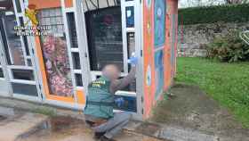 Un investigador de la Guardia Civil toma huellas en una máquina expendedora.
