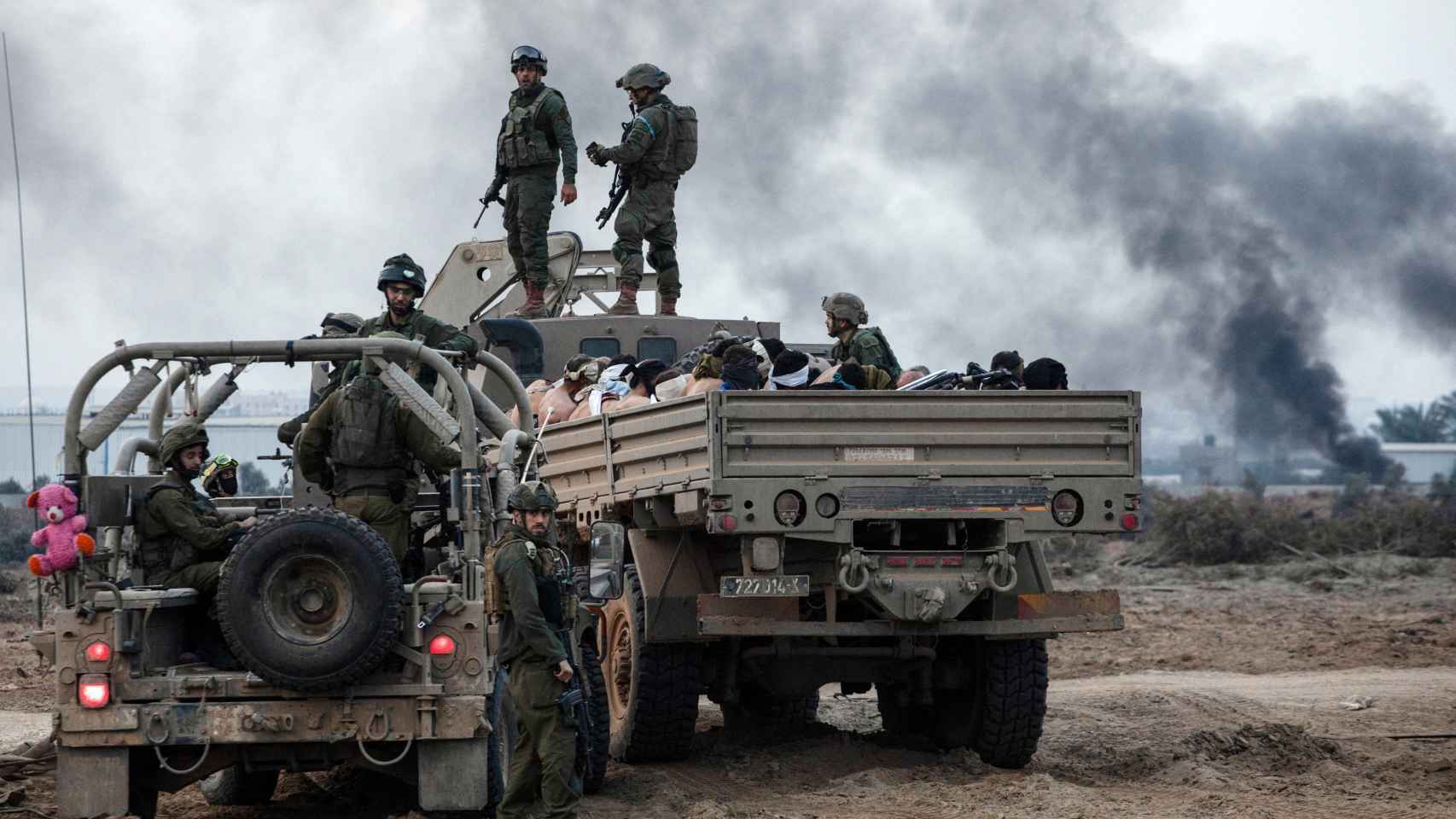Los detenidos palestinos se sientan en un camión mientras los soldados israelíes hacen guardia en medio del conflicto.