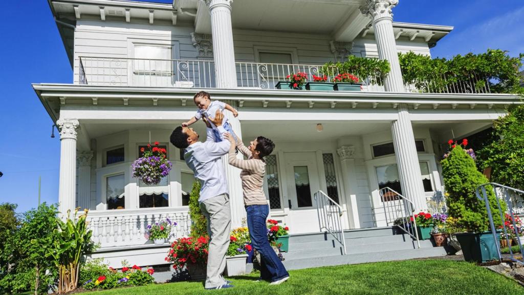 Familia frente a su casa con jardín.