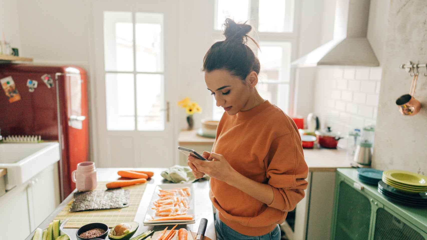 Imagen de una mujer revisando recetas en línea mientras cocina