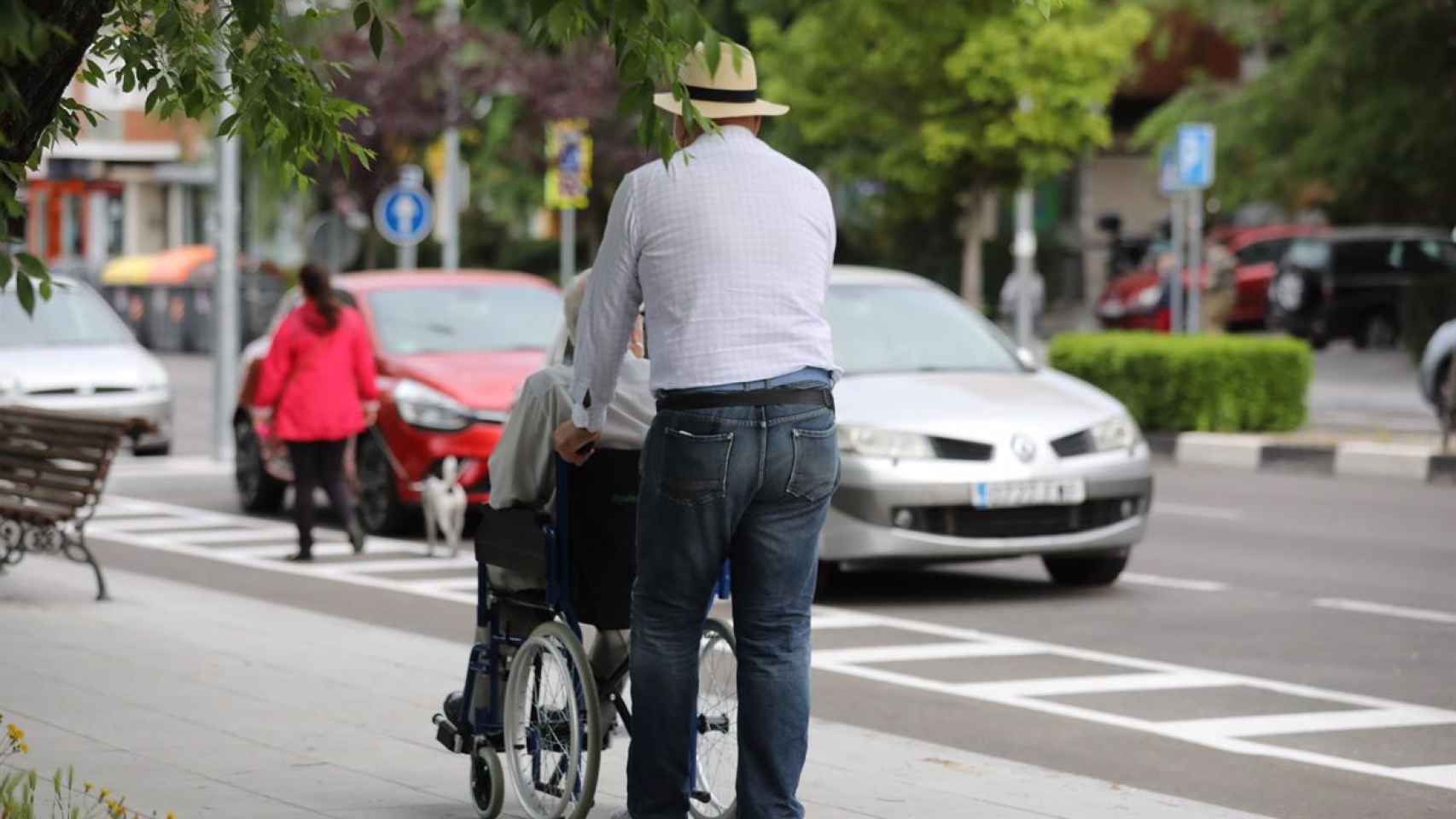 Un hombre pasea con una persona en silla de ruedas, en Madrid