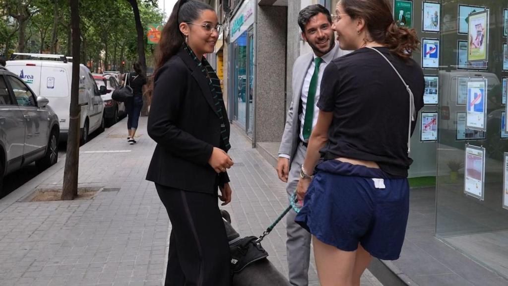 Dos jóvenes miran ofertas de pisos de segunda mano en un escaparate