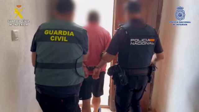 Agentes de la Guardia Civil y de la Policía Nacional custodian a uno de los detenidos.