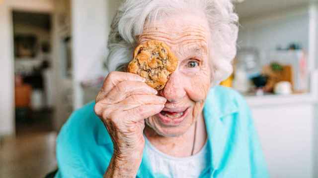 Una mujer centenaria posa para una foto con una galleta.