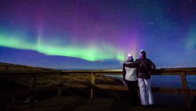 Una pareja disfrutando de una aurora boreal