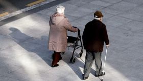 Una imagen de dos personas mayores caminando por la calle.