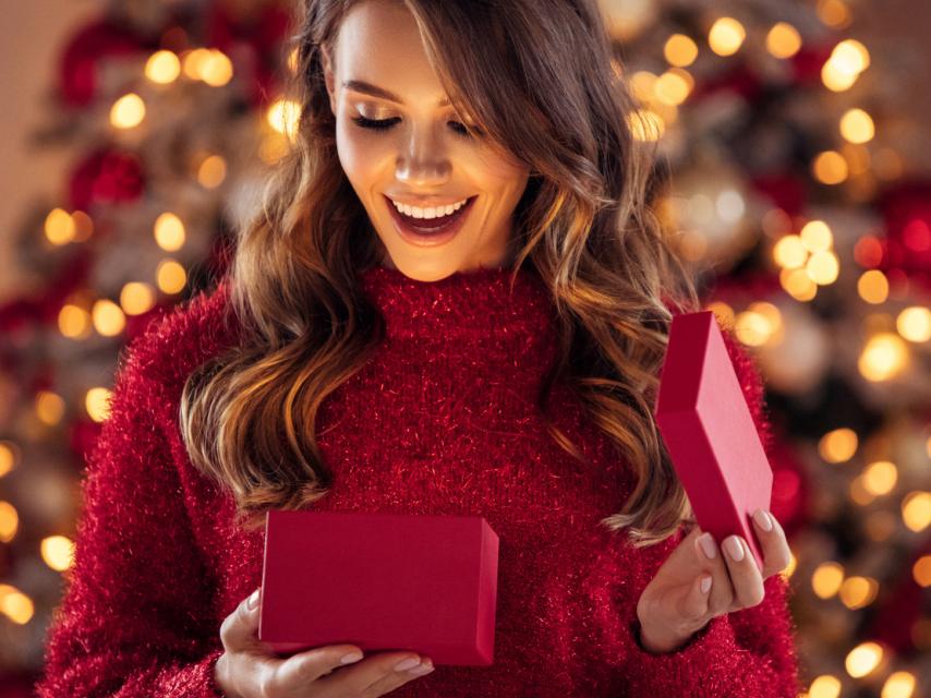 Mujer sorprendida abriendo un regalo.