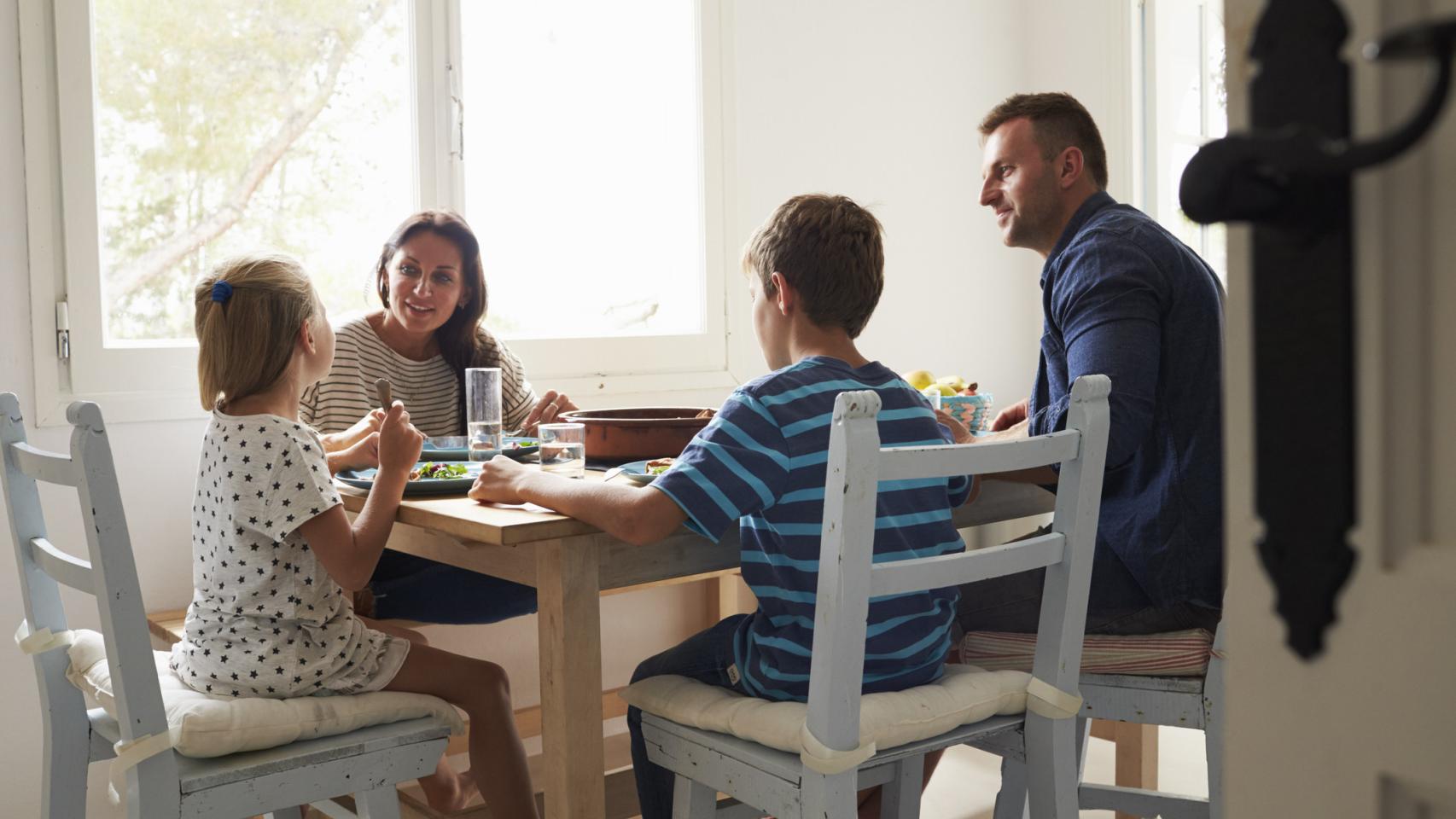 Una familia reunida en torno a la mesa en la cocina.