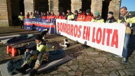 Bomberos sujetan una pancarta durante una concentración en forma de protesta pacífica, en la Praza do Obradoiro