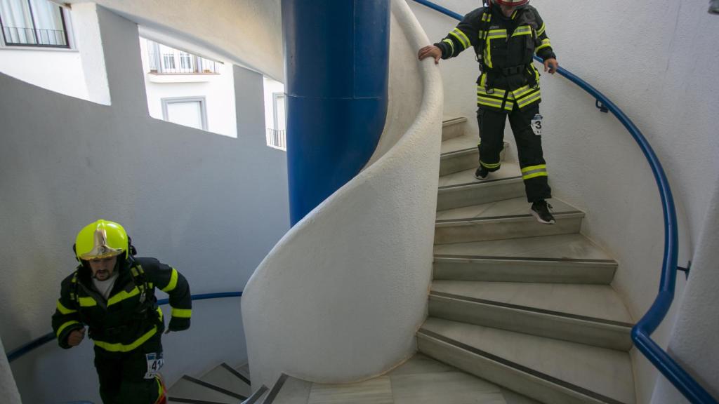 Unos bomberos por las escaleras.