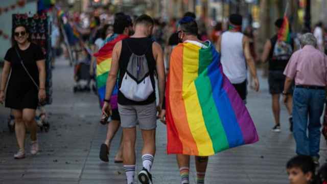 Dos personas paseando por Madrid, una de ellas con la bandera LGTB.